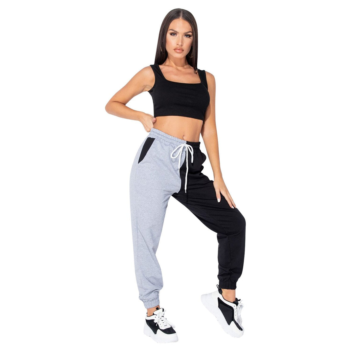 Woman wearing black crop top with gray and black pants on a white background