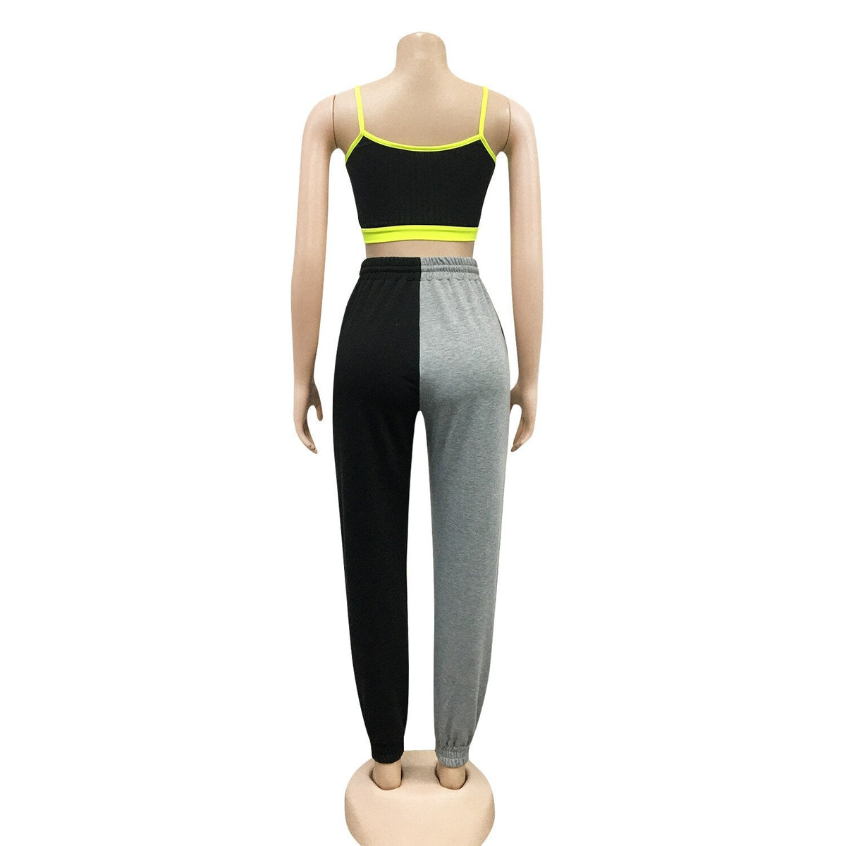 Woman wearing black crop top with yellow trim and gray and black pants